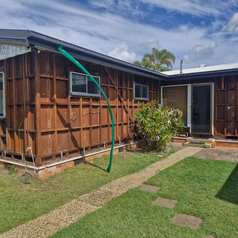 House exterior with wall cladding removed to expose timber framing