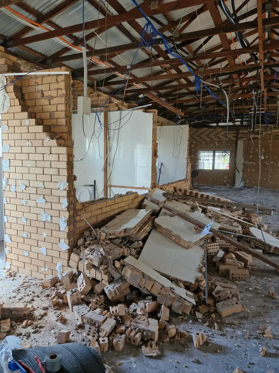 Pile of brick and wall debris inside a partially demolished building