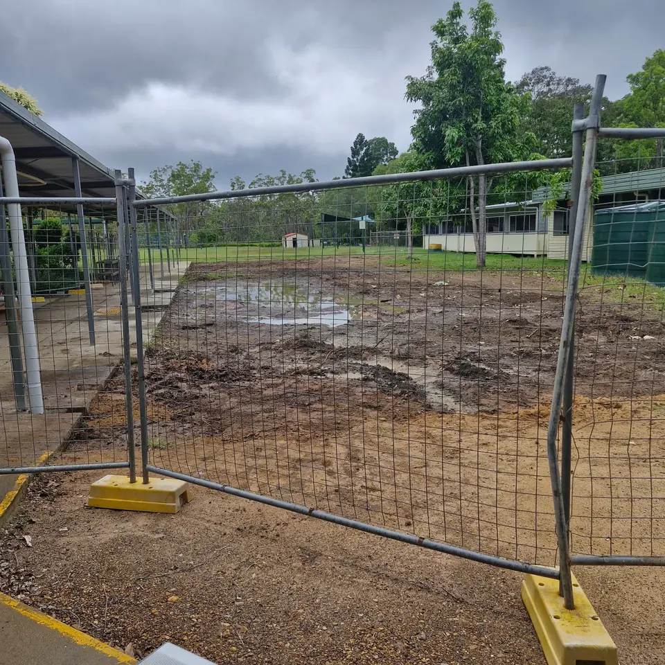 Fenced work area with disturbed ground and temporary site barriers